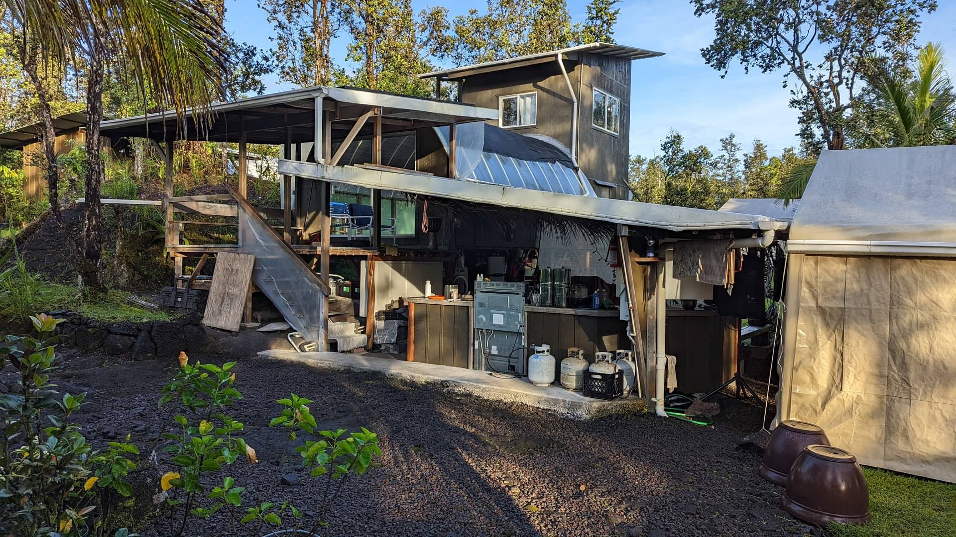 Rustic off-grid homestead kitchen with propane tanks in tropical forest setting