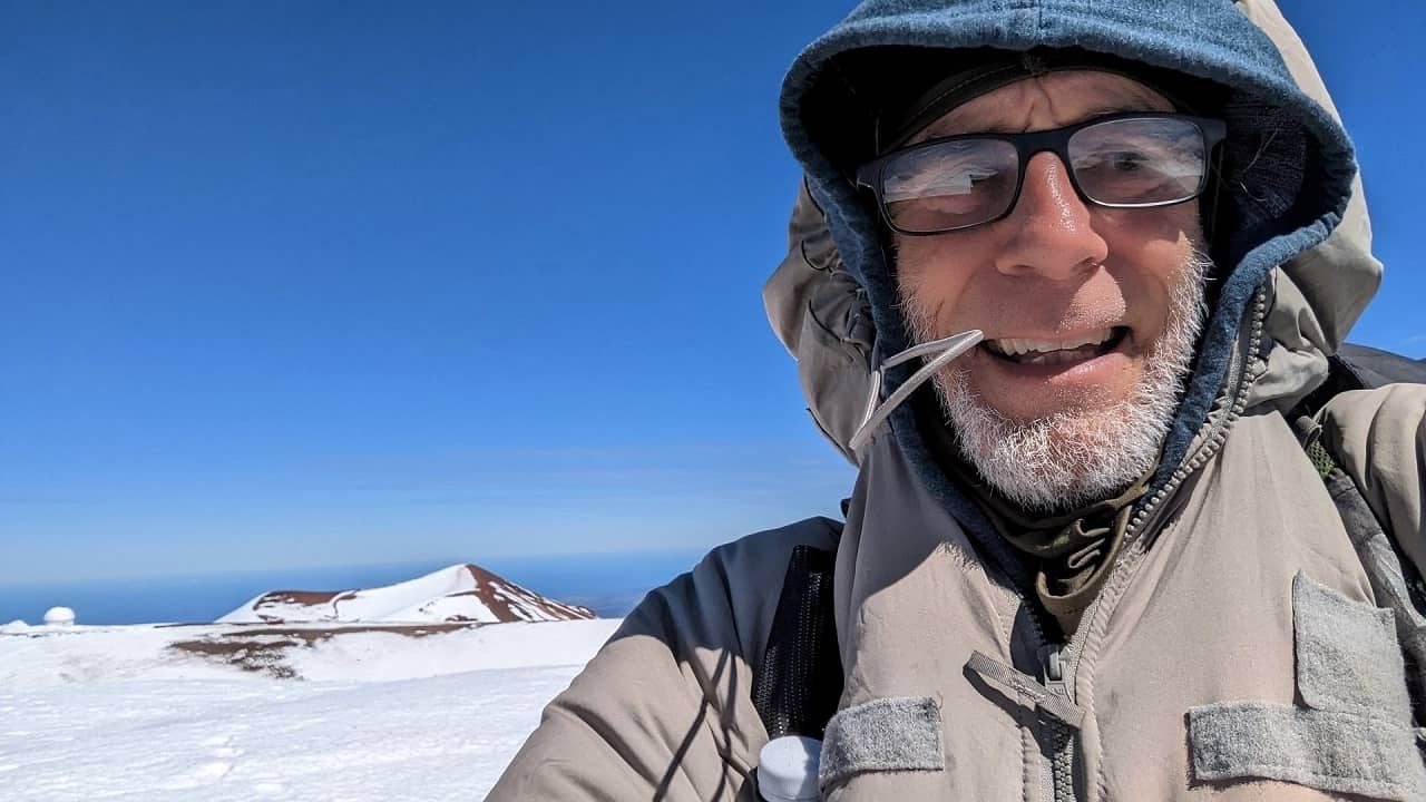 Picture of Benedick Howard at the summit of MaunKea with snow in Hawaii
