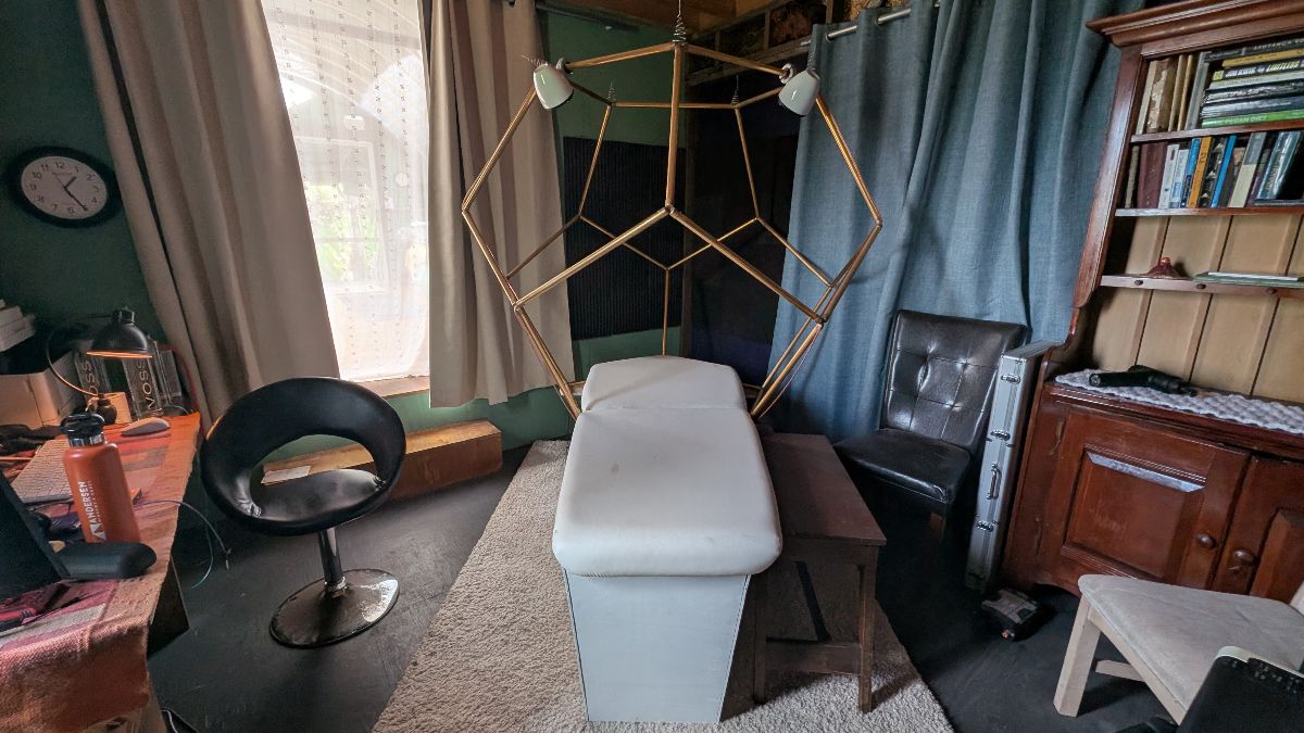 Cozy therapy room with sound healing musical massage table under gold plated dodecahedron geometric metal frame