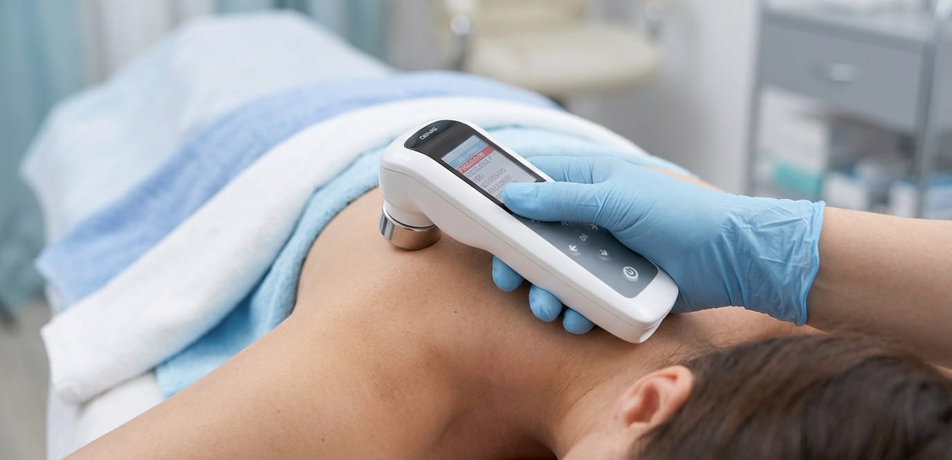 Gloved clinician performing ultrasound therapy on a patient's shoulder for physiotherapy pain relief.