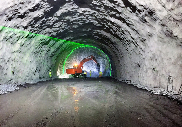 Underground tunnel construction with excavator, workers, and green laser guidance